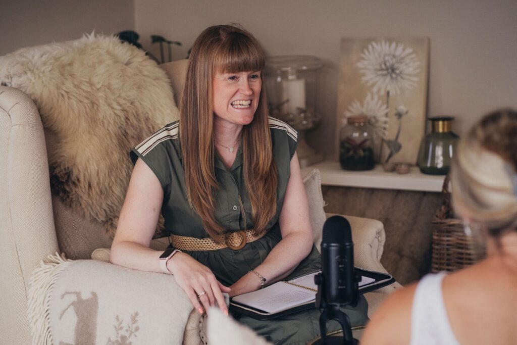 Kath smiling during a relaxed online organising consultation with a notebook and microphone